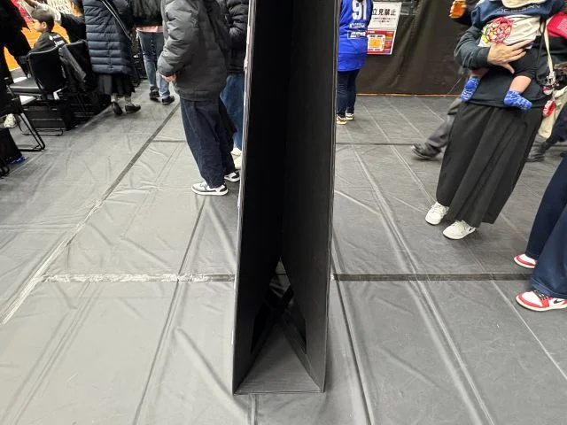 スポーツ会場で使用される自立式パネルの側面。ブラック仕様のパネルが自立して設置されており、イベント会場や試合会場で案内・装飾・フォトスポットとして活用される様子