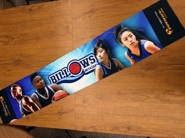 バスケットボール選手の写真とチームロゴをフルカラーでデザインした、スポーツチームの応援・選手グッズ向けオリジナルマフラータオル。